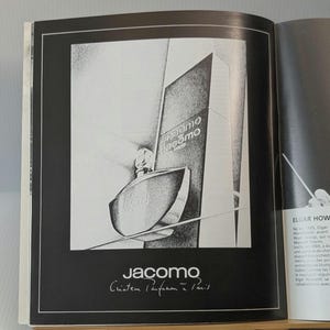May include: A black and white advertisement featuring a perfume bottle with a rounded base and a rectangular box labeled Jacomo Paris. The text Jacomo Créateur Parfumeur à Paris is printed at the bottom of the page in a clean, sans-serif font.
