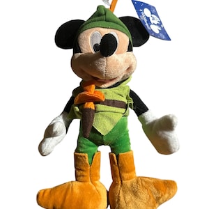 Pu&ograve; includere: Un peluche di Topolino vestito da Robin Hood. Il giocattolo presenta un cappello, una tunica e stivali verdi, con una cintura marrone e una piuma. Mickey ha orecchie nere, viso color camoscio e guanti bianchi. Un'etichetta blu &egrave; attaccata.