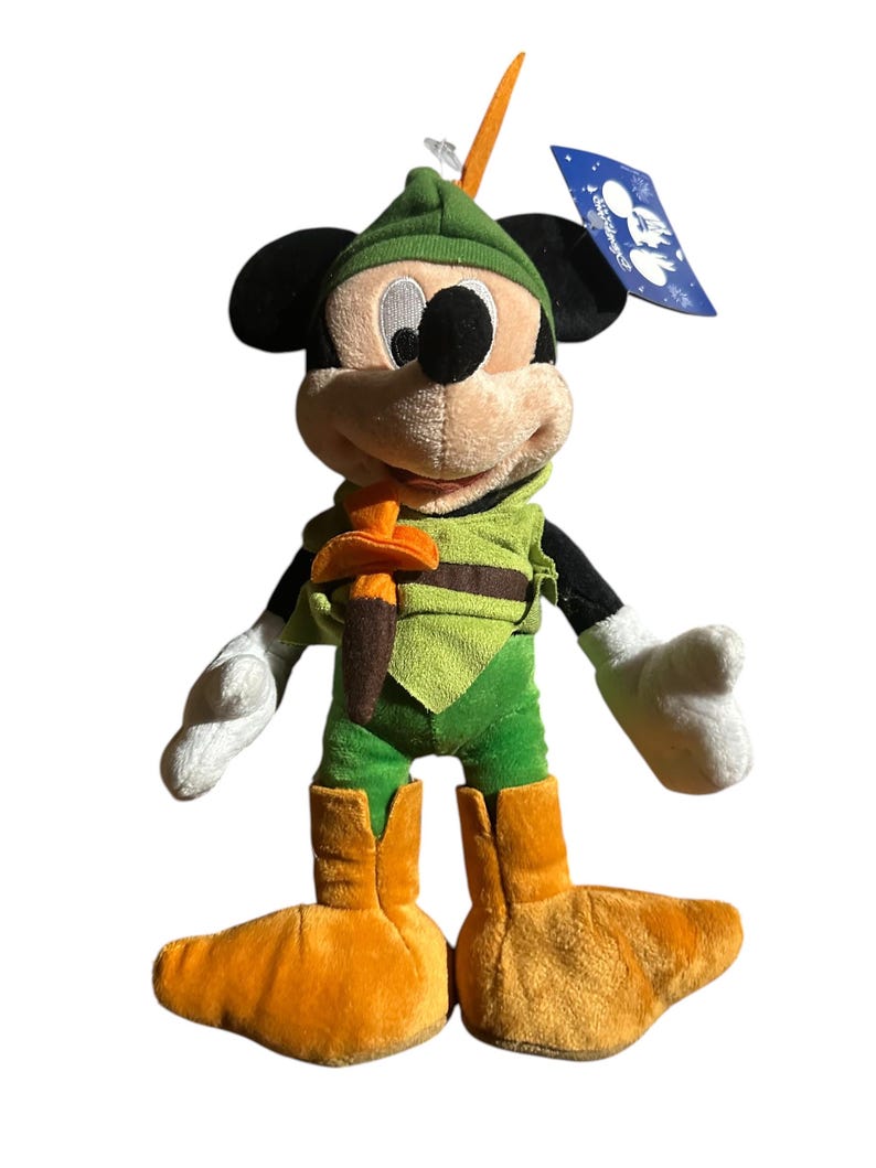 Pu&ograve; includere: Un peluche di Topolino vestito da Robin Hood. Il giocattolo presenta un cappello, una tunica e stivali verdi, con una cintura marrone e una piuma. Mickey ha orecchie nere, viso color camoscio e guanti bianchi. Un'etichetta blu &egrave; attaccata.