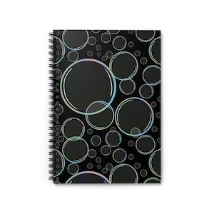 Può includere: Quaderno a spirale con copertina nera con un motivo di bolle iridescenti di varie dimensioni. Le bolle hanno una sottile lucentezza colorata sullo sfondo scuro, creando un design giocoso e accattivante.