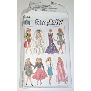 May include: A Simplicity sewing pattern envelope featuring illustrations of various doll fashions. The designs include a wedding dress, formal gowns, and casual outfits. The envelope is white with the Simplicity logo and pattern number.