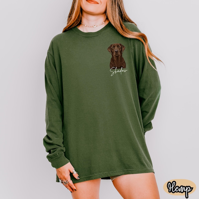 May include: Olive green long-sleeve shirt featuring a brown Labrador Retriever illustration with the name "Shadow" in a cursive font. The shirt is made of a soft material and has a relaxed fit. The word "Hemp" is in a small oval at the bottom right.