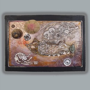 May include: Mixed media artwork with a black frame. The artwork features a skeletal figure, skulls, and various metallic and textured elements. The color palette includes shades of brown, purple, and silver, creating a unique and detailed composition.