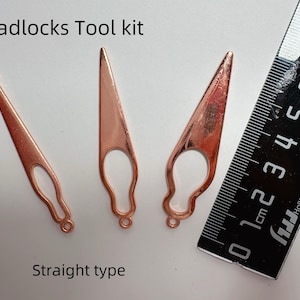 May include: Three copper-colored dreadlocks tools with a ruler. The tools are straight type and have a teardrop-shaped handle with a loop at the end. The ruler is black with white markings and the text "Dreadlocks Tool kit" and "Straight type".