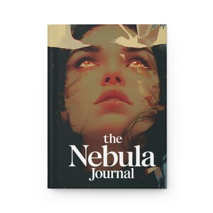 May include: A hardcover journal titled "the Nebula Journal" features a stylized illustration of a woman's face with glowing eyes. The cover art has a celestial theme with a dark background and white text.