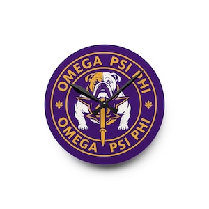 May include: A round wall clock with a purple background and gold border. The center features a white bulldog illustration with a gold star and spear emblem. The text OMEGA PSI PHI is printed in gold around the perimeter with two small star icons.