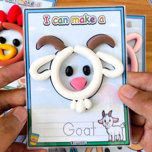 Puede incluir: Una tarjeta con el texto "I can make a" y un dise&ntilde;o de cabra de arcilla. La cabra tiene detalles blancos, marrones, negros y rosas. La palabra "Goat" est&aacute; escrita debajo en l&iacute;neas punteadas, con una ilustraci&oacute;n de cabra. La tarjeta es sostenida.