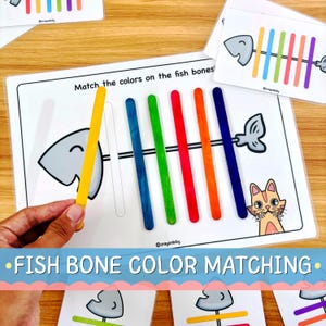 May include: A color matching activity sheet featuring a fish skeleton illustration with the text Match the colors on the fish bones. The set includes colorful wooden craft sticks in yellow, blue, green, red, orange, and dark blue.