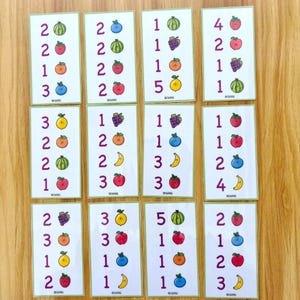 May include: A collection of educational flashcards featuring numbers and colorful fruit illustrations. Each card displays a number and a corresponding set of fruits, such as apples, grapes, and watermelons. The cards are designed for learning and counting.