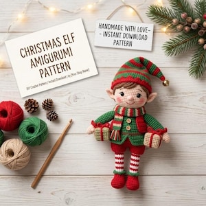 Könnte beinhalten: Eine gehäkelte Weihnachts-Elfenpuppe mit einer rot-grün gestreiften Mütze mit Glöckchen, einer grünen Weste und rot-weiß gestreiften Leggings. Die Elfe hält zwei kleine Geschenke. Daneben liegen Wollknäuel, eine Häkelnadel und ein Schild mit der Aufschrift CHRISTMAS ELF AMIGURUMI PATTERN.