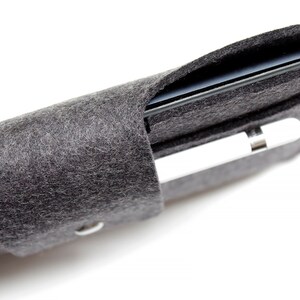 K&ouml;nnte beinhalten: Eine graue Filzh&uuml;lle f&uuml;r ein iPad und einen Apple Pencil. Die H&uuml;lle ist aufgerollt und das iPad und der Pencil sind im Inneren sichtbar.