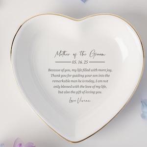 Op de afbeelding: Een hartvormige, witte keramische sieradenschaal met een gouden rand. De schaal heeft de tekst "Mother of the Groom" en een persoonlijke boodschap. Een attent cadeau voor een bruiloft.