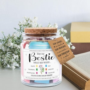 May include: A glass jar with a cork lid, filled with colorful paper strips. The jar has a label that reads "Hey my Bestie, Read me when..." and a tag with a message about friendship. The jar is decorated with flowers.