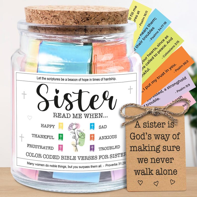 May include: A glass jar with a cork lid, filled with colorful Bible verses for a sister. The jar has a label that reads "Sister, Read Me When..." and includes a tag with a quote about sisters. The verses are color-coded.