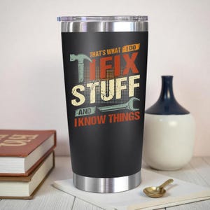 May include: A black stainless steel tumbler with a silver rim and lid. The tumbler features the text "THAT'S WHAT I DO, I FIX STUFF AND I KNOW THINGS" with tool graphics in a distressed style.