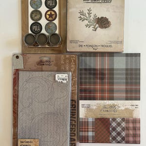 May include: A collection of craft supplies including a die-cut set with a pinecone and leaf design, a set of decorative pull labels, a harlequin elements embossing folder, and a pack of plaid patterned paper sheets.