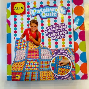 Puede incluir: Un kit de artesanía de colcha de retazos colorido para niños de 7 años en adelante. La caja presenta a una niña sosteniendo una aguja e hilo, y una colcha colorida con una variedad de patrones. El texto en la caja dice "Lace together 24 squares to make a keepsake quilt! It's easy! No stitching! Just lacing!"