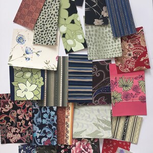 May include: Assortment of vintage wallpaper samples in various patterns and colors, including floral, geometric, and paisley designs. The samples are arranged in a random pattern on a white background.