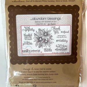 May include: A clear plastic package containing a rubber stamp set. The set includes stamps with floral designs and sentiments like "Thank You" and "Happy Birthday." The package also includes instructions and the text "abundant blessings."