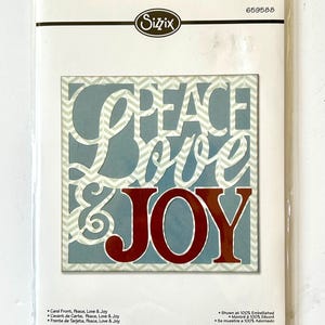 May include: A set of four metal dies for crafting. The dies feature a chevron pattern and the words "Peace, Love & Joy" in a red and blue color scheme. The dies are packaged in a clear plastic bag with a white card backing.