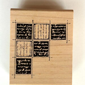 May include: A rectangular wooden stamp with six black text blocks arranged in a grid pattern. The text appears to be in a script font. The stamp is made of light-colored wood.