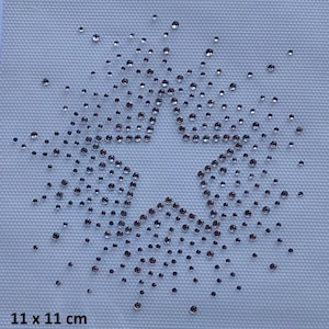 May include: A star-shaped design made of small, sparkling rhinestones on a light-colored fabric. The rhinestones are arranged to form a star outline, with the center of the star left open. The fabric measures 11 x 11 cm.