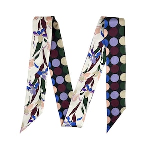 May include: A silk scarf with a floral and polka dot design. One side has a cream background with purple, blue, and pink flowers. The other side has a black background with large polka dots in various colours. The scarf is long and narrow.