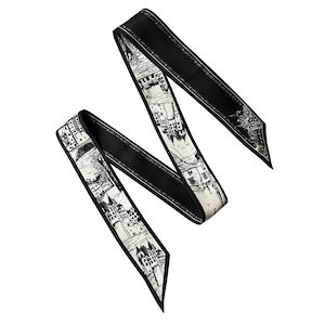 Könnte beinhalten: Schwarz-weißer Seidenschal mit einem Stadtbild-Druck. Der Schal hat einen schwarzen Rand mit einer weißen Linie.