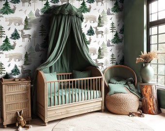 May include: A green canopy crib with a white and green woodland animal print wallpaper. The wallpaper features bears, deer, and trees. The crib is in a nursery with a wicker chair and a wooden dresser.