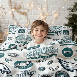 Könnte beinhalten: Weißes Bettwäsche-Set mit dem Logo und Text der Philadelphia Eagles. Das Set enthält einen Kissenbezug und eine Bettdecke mit den Worten "Super Bowl Champions" und "Eagles". Das Design ist in Grün und Weiß gehalten.