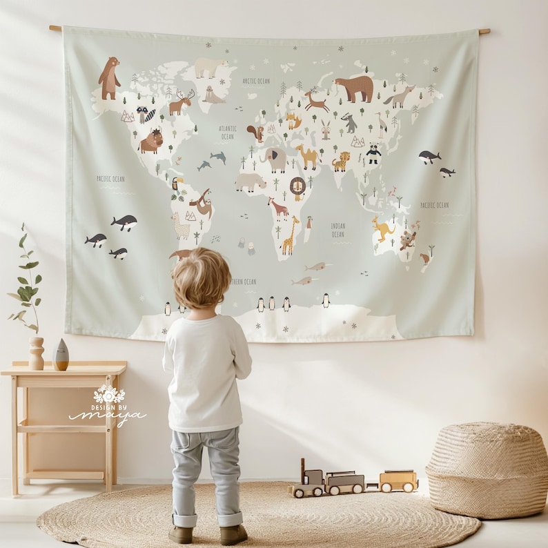 Pode incluir: Uma tape&ccedil;aria de mapa-m&uacute;ndi verde claro com ilustra&ccedil;&otilde;es de animais e oceanos. O mapa est&aacute; pendurado em uma haste de madeira. Uma crian&ccedil;a est&aacute; em frente ao mapa. O texto "DESIGN BY maya" &eacute; vis&iacute;vel.