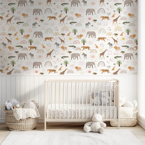 Op de afbeelding: Een kinderkamer met een witte wieg, een rieten mand met knuffels en een wit tapijt. Het behang heeft een herhalend patroon van safaridieren, regenbogen en bomen in zachte kleuren.