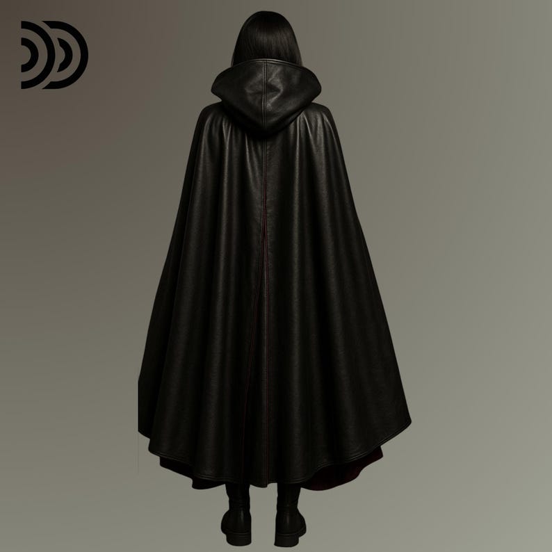 Pode incluir: Uma capa preta com capuz com uma apar&ecirc;ncia texturizada. A capa tem um design longo e fluido e uma costura vermelha nas costas. A pessoa est&aacute; usando botas pretas. A imagem &eacute; tirada de tr&aacute;s.