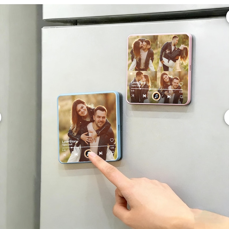 May include: Two square magnets with photos of a couple, one with a blue border and the other with a pink border. The magnets display a music player interface with the text "Love Story". A finger touches the play button on one magnet.