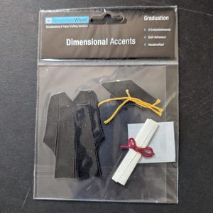 May include: A package of three self-adhesive graduation embellishments. The embellishments are black, white, and yellow and include a graduation cap, gown, and diploma. The package says "Remember When" and "Dimensional Accents".