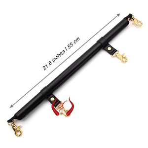May include: Black leather accessory with gold-colored clasps and hardware. The accessory measures 21.6 inches or 55 cm in length. The accessory has a red and gold decorative element.