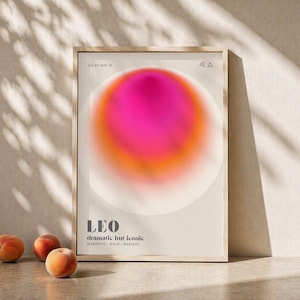 Könnte beinhalten: Ein gerahmter Kunstdruck mit einem leuchtenden rosa und orangefarbenen abstrakten Design, betitelt "LEO dramatic but iconic". Der Druck wird mit drei Pfirsichen präsentiert. Der Rahmen ist aus hellem Holz.