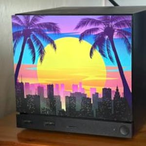 May include: A black computer case featuring a front panel graphic of a city skyline at sunset with two palm trees in the foreground. The sky transitions from purple to orange and yellow, with a large yellow sun behind the dark city buildings.