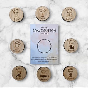 Può includere: Una collezione di bottoni di legno "Brave" con vari nomi e illustrazioni di animali, tra cui un orso, una volpe e uno squalo. Una carta al centro recita "A Special Brave Button" e include un messaggio sul coraggio.