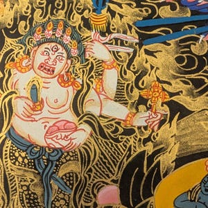 May include: A detailed painting of a deity with multiple arms, holding various objects. The deity is depicted with a fierce expression and a crown of flames. The painting is done in a traditional style with vibrant colors and intricate details.