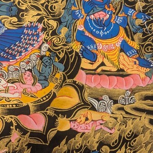 May include: A colorful Tibetan Buddhist thangka painting depicting a deity with multiple arms and heads. The deity is surrounded by other figures and symbols, all rendered in intricate detail. The painting is done on a dark background with gold accents.