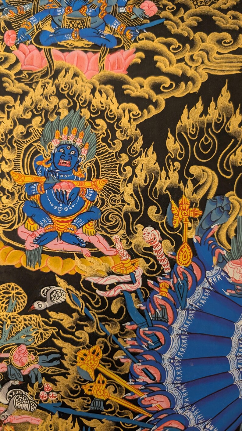 May include: A colorful Tibetan Buddhist thangka painting depicting a deity with multiple arms and hands, surrounded by intricate patterns and symbols. The deity is blue and has a fierce expression, holding a musical instrument in one hand. The background is black with gold and red accents.