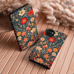 May include: Two phone cases with a floral pattern. The cases have a dark teal background with red, orange, and yellow flowers and green leaves. The cases are on a wooden surface.