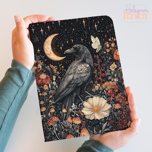 May include: A decorative tablet cover with a detailed illustration of a raven in a floral landscape under a starry night sky. The design includes a crescent moon, a butterfly, and various flowers and mushrooms.