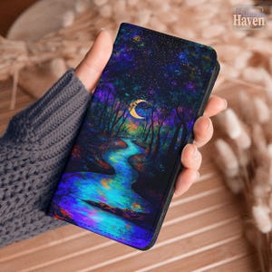 May include: A rectangular phone case featuring a vibrant, colorful illustration of a night forest scene with a glowing blue river, dark silhouetted trees, a bright yellow crescent moon, and a starry sky in shades of purple, blue, and green.