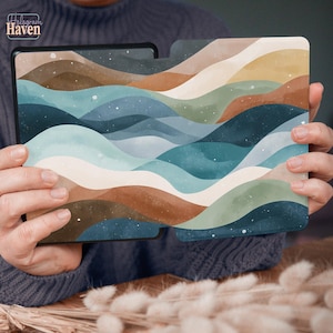 May include: A tablet case featuring a watercolor landscape design with rolling hills in shades of brown, blue, green, and beige. The case is held by a person. The brand name "Hologram Haven" is visible in the upper left corner.