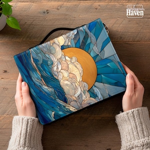 May include: A clutch with a vibrant ocean-themed design featuring a golden sun, stylized waves, and geometric blue shapes. The clutch has a black handle and the text "Hologram Haven".
