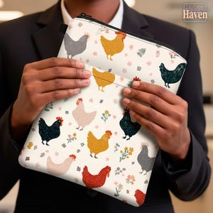 Puede incluir: Una bolsa con cremallera de color crema con un patrón repetido de gallinas coloridas y detalles florales. Las gallinas son de varios colores, incluyendo negro, amarillo, rojo y gris. La bolsa es sostenida por una persona que lleva un traje negro.