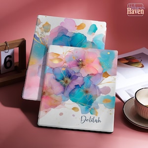 May include: Two notebooks with floral watercolour designs in pink, blue, and purple hues. The notebooks have the name "Delilah" printed on the cover. The top right corner of the image has the text "Hologram Haven".