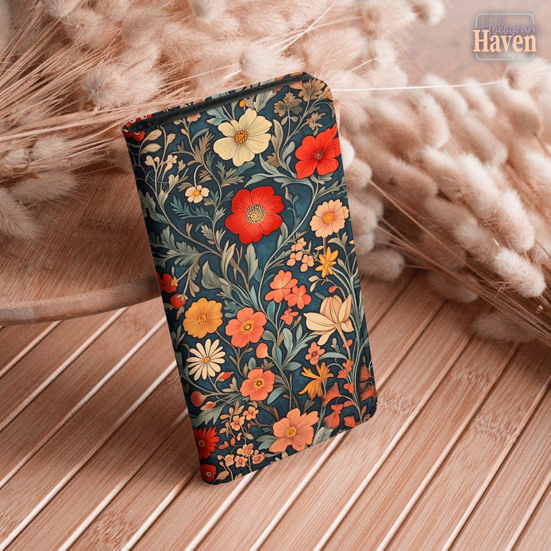 May include: A rectangular case with a floral pattern featuring red, yellow, and orange flowers on a dark teal background. The case is decorated with a botanical design and the text "Haven" is visible in the upper right corner.